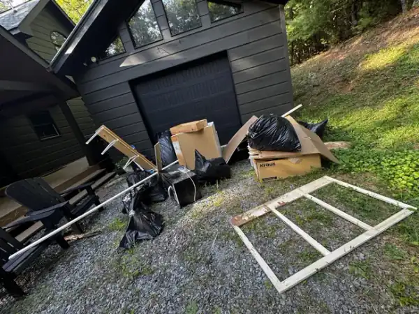 Garage exterior before — boxes and debris piled on gravel